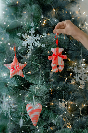 A woman's hand decorates the Christmas tree with fabric toys. DIY Christmas decor.の写真素材