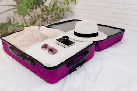 An open suitcase with women's clothes on the bed is collected for travel.の写真素材