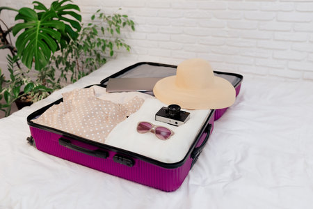 An open suitcase with women's clothes on the bed is collected for travel.の写真素材