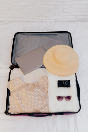 An open suitcase with women's clothes on the bed is collected for travel.の写真素材