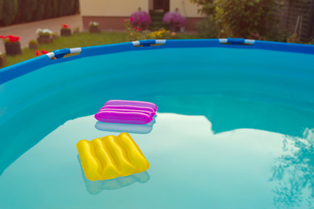 Two inflatable pillows, yellow and purple, lie on the surface of the water. beach accessories.の写真素材