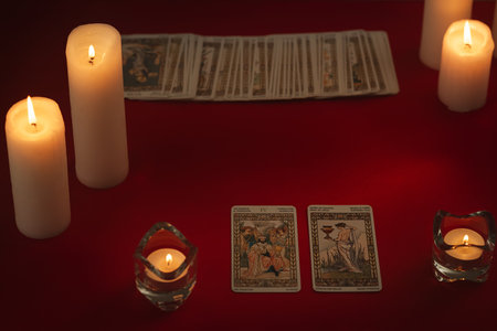 The layout of tarot cards by candlelight on a red background. Tarot cards and esoteric concept. magic rituals.の写真素材