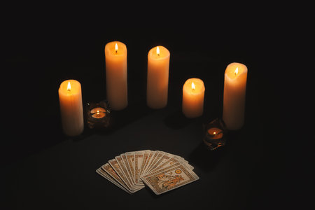 Layout of tarot cards by candlelight on a black background. Tarot cards and esoteric concept. magic rituals.の写真素材