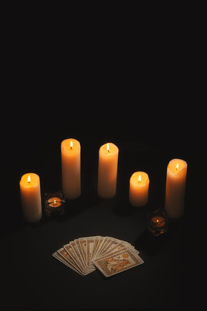 Layout of tarot cards by candlelight on a black background. Tarot cards and esoteric concept. magic rituals.の写真素材