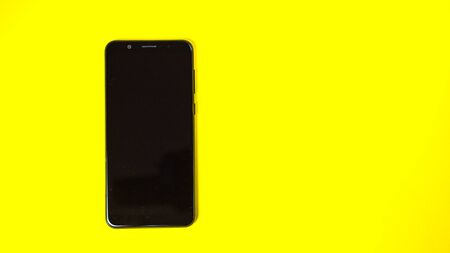 black phone on yellow background. top view. copy space.の写真素材