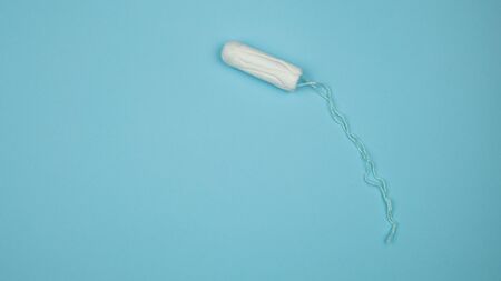 Medical female tampon on a blue background. Hygienic white tampon for women. Cotton swab. Menstruation, means of protection. Tampons on a red background.の写真素材