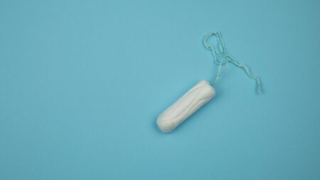 Medical female tampon on a blue background. Hygienic white tampon for women. Cotton swab. Menstruation, means of protection. Tampons on a red background.の写真素材