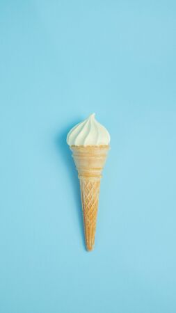 Vanilla ice cream cone on blue faded pastel color background. Vanilla ice cream in wafer cup.の写真素材