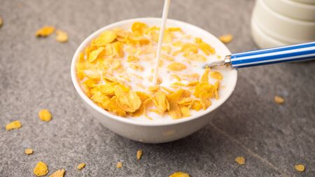 closeup of corn flakes falling in a white bowl isolated on white background.