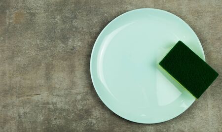 Cleaning sponge on a green plate on a gray background.