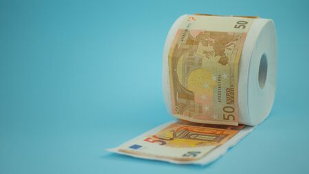 Panic buys the concept of the Covid-19 coronavirus outbreak. Roll of toilet paper with euro banknotes on blue background.の写真素材