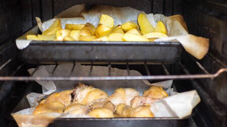 chicken drumsticks and potatoes are roasted in the oven on baking paper. close up.の写真素材