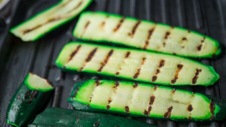 grilling organic zucchini on a grill pan. Close-up grilled vegetables sliced veggie snacking process. food on quarantine.の写真素材