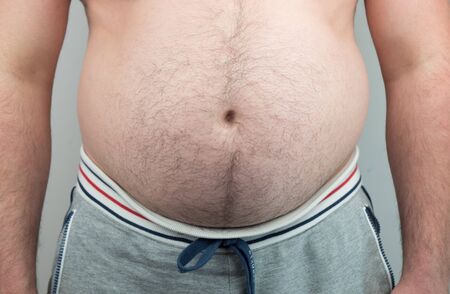 Close up of Man touching his fat belly, Mens hand holding excessive belly fat. Being overweight is...