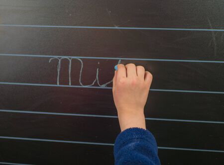 Little schoolboy writing on blackboard at home.