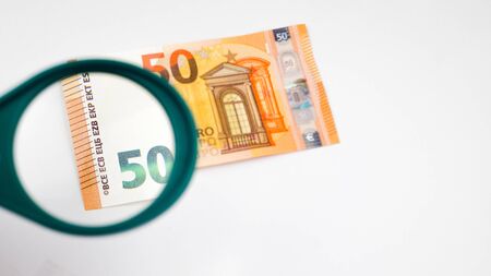 50 euro banknotes under a magnifying glass on a white table.の写真素材