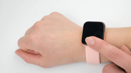 Woman's hand touching the screen of a smart watch on white background.