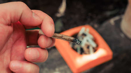Man smoking cigarette and using an ashtray.