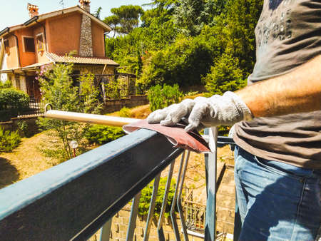 a gloved worker cleans the fence with sandpaper.の写真素材