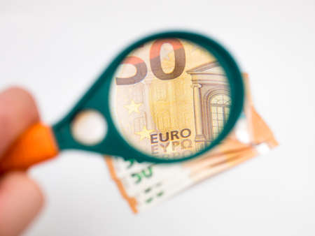 Banknotes of 50 euros under a magnifying glass on a white background.の写真素材