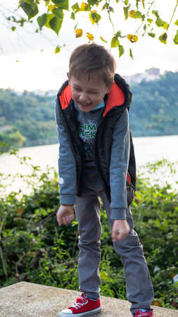 boy sitting on a bench in a medical mask, autumn parkの写真素材