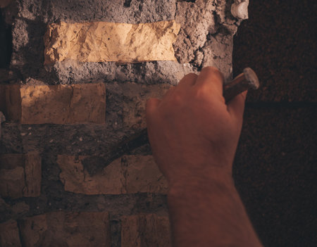 builder punches a hole in the wall with a hammer, close upの写真素材