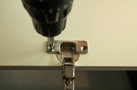 The master attaches accessories to furniture details. Assembly of cabinet furniture