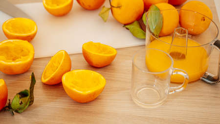 Squeezed orange juice and fresh oranges fruits on wooden table