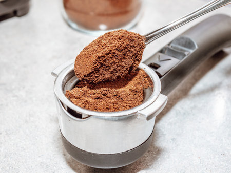 person makes coffee in a coffee machine picks up ground coffee with a spoon from a coffee grinder drawerの写真素材
