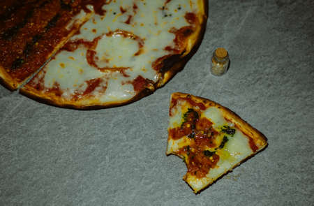 slice of bitten pizza on a gray tableの写真素材