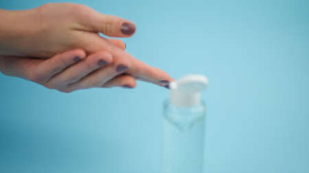 Human hand plastic bottle using alcohol gel to do the cleaning. isolated blue background.   copy spaceの写真素材