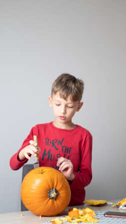 Boy busy carving a pumpkin jack-o-lantern for Halloween - removing the seedsの写真素材