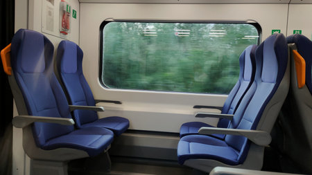 Train window with blurred landscape and empty seats.