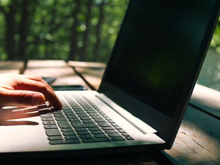 Laptop stands on a wooden table outdoors