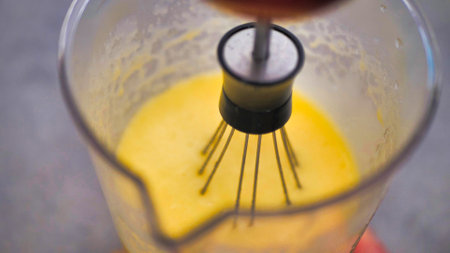 Beat eggs with a whisk mixer in a transparent glassの写真素材