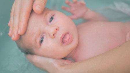 A happy four month old smiling baby is taking a bath. Smiling child in bathroom with mother. Washing and bathing babies.の写真素材