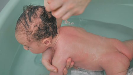 A charming baby is bathing in the bathroom. He lies on his stomach.の写真素材