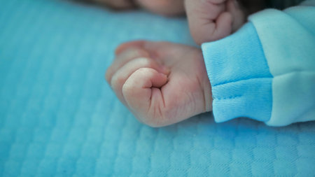 Babys hand over blue blanket. Sentimental moment with a resting toddler. Tiny hand of a newborn son.の写真素材