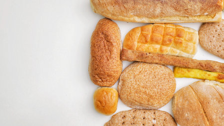 Bread and Bakery Products Isolated on White. Different types of bread: sesame bun, baguette, baked rolls, rustic bread, round bun, sesame bun.の写真素材