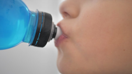 Taking a break. Side view of sporty teenager drinking blue energy drink. Youth and sportsの写真素材