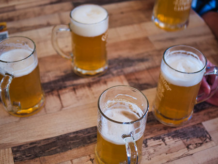 glasses of light beer displayed in a circle on a wooden table. Overhead beer glasses on a wooden table.の写真素材