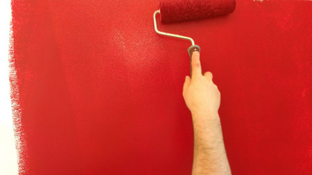 painting a wall. painting the wall in red with a rollerの写真素材