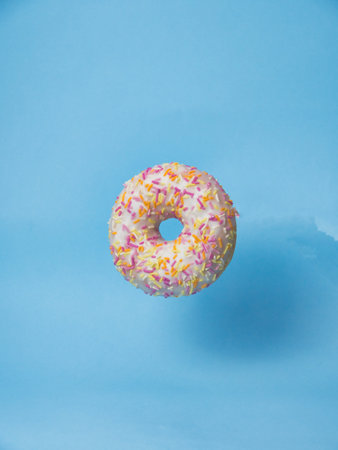 Pink donut on a blue background, side view, dessert concept, copy space, blue backgroundの写真素材