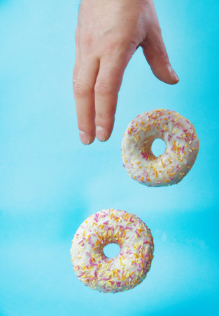 hand takes a delicious donut on a blue backgroundの写真素材