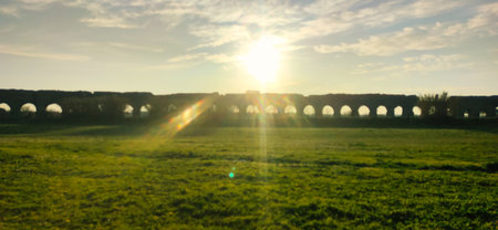 Sunrise over ancient arches in a serene landscape bathed in golden lightの写真素材