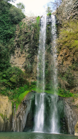 Two cascading waterfalls flow gracefully down rocky cliffs amidst lush greenery in a serene natural oasis Generative AIの写真素材