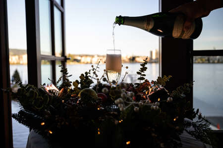 Pouring champagne into the glass by the lake
