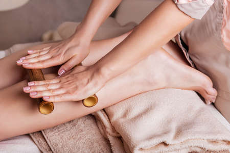 Massage of human foot in spa salon  with bamboo sticks.Closeup of feet, Caucasian woman having a massage spa salonの写真素材