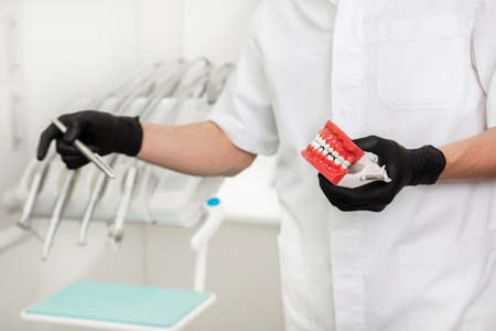 dentist showing human teeth with ceramic dentures. Male hands wearing medical gloves holding open...