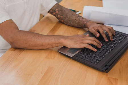 Mens hands with tattoo closeup, typing on laptop keyboard.の写真素材